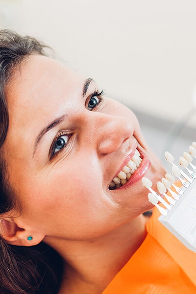A woman smiling as the dentist places her a palette of different tooth shades