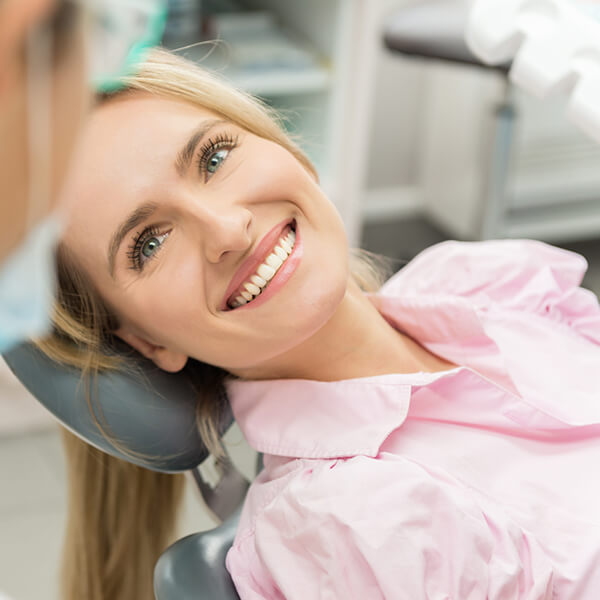 A woman lying in the dentist chair while smiling