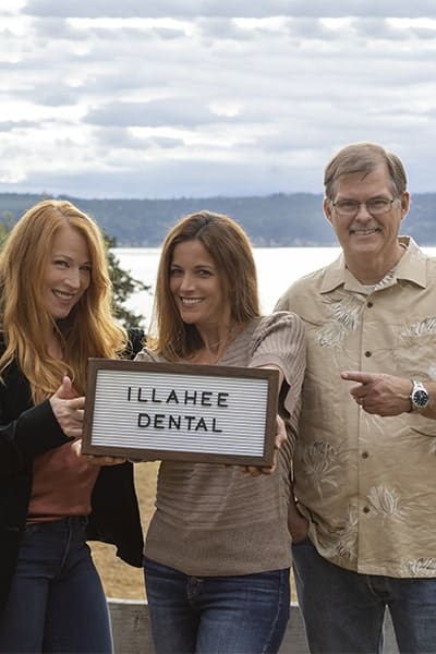Get the dental care your family deserves Our three Illahee Dental specialists holding a sign