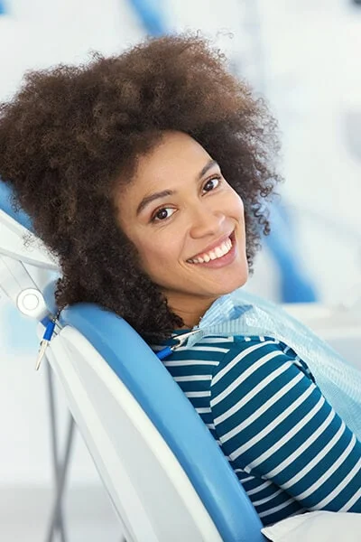 A woman sitting in the dentist's chair while smiling